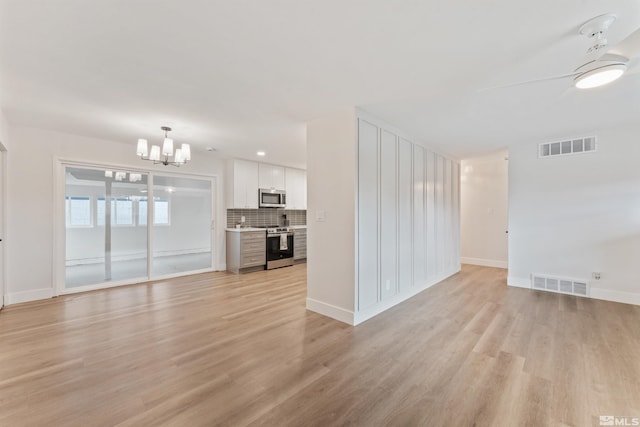 unfurnished living room featuring ceiling fan with notable chandelier and light wood-type flooring