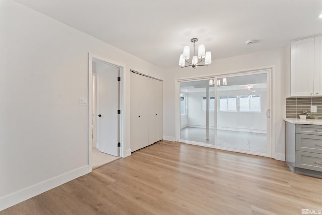 unfurnished dining area with a chandelier and light hardwood / wood-style flooring