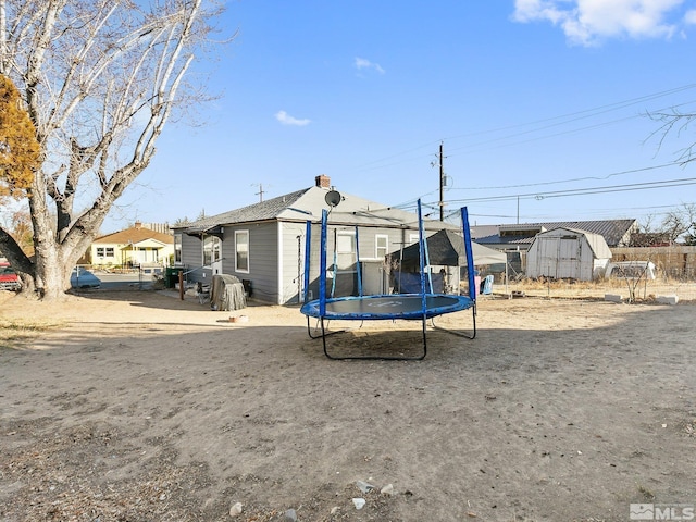 rear view of property with a shed and a trampoline