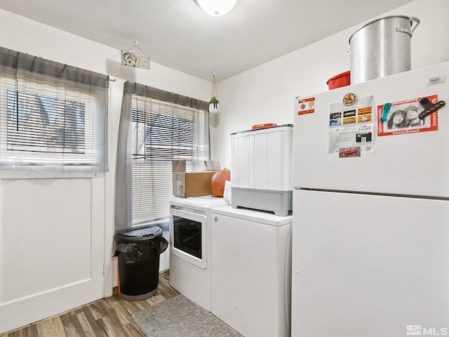 laundry area featuring washer and clothes dryer, cabinets, plenty of natural light, and light wood-type flooring