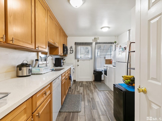 kitchen featuring light stone countertops, dark hardwood / wood-style flooring, white appliances, and sink