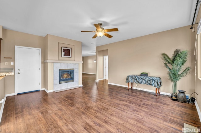 living room featuring dark hardwood / wood-style floors, ceiling fan, and a fireplace