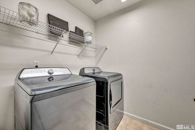 clothes washing area featuring light tile patterned floors and washing machine and dryer