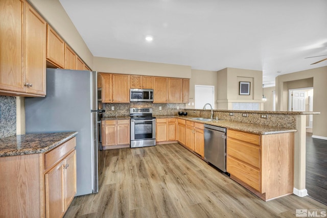 kitchen featuring kitchen peninsula, sink, appliances with stainless steel finishes, and light hardwood / wood-style flooring