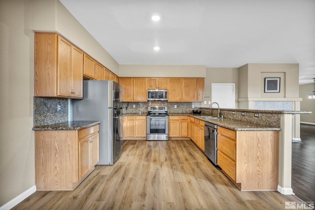 kitchen with dark stone counters, light wood-type flooring, and appliances with stainless steel finishes