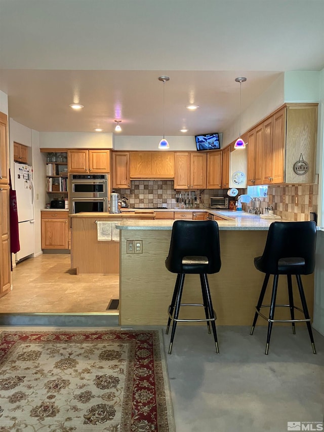 kitchen featuring white fridge, a kitchen bar, kitchen peninsula, and tasteful backsplash