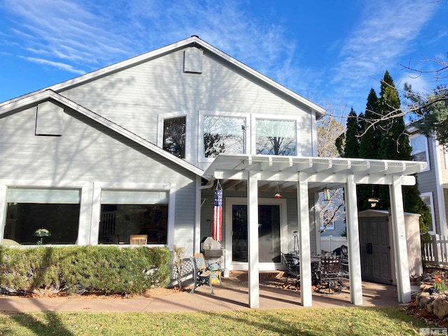 back of property with a pergola and a shed