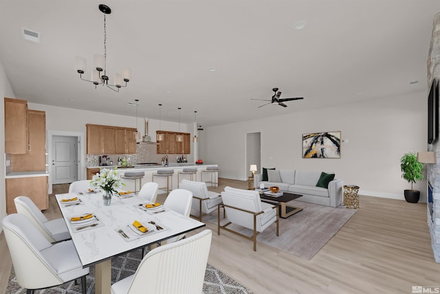 dining space with ceiling fan with notable chandelier and light hardwood / wood-style floors