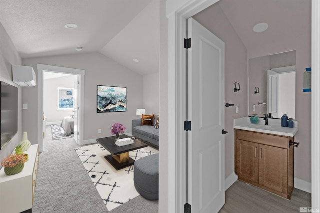 interior space featuring a textured ceiling, a wall mounted air conditioner, vanity, and lofted ceiling