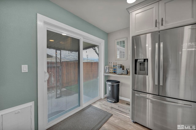 kitchen with white cabinetry, stainless steel refrigerator with ice dispenser, and light hardwood / wood-style flooring