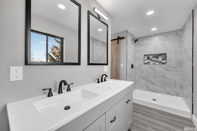 bathroom with tiled shower, vanity, and hardwood / wood-style flooring