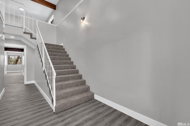 staircase with hardwood / wood-style floors, high vaulted ceiling, and beam ceiling