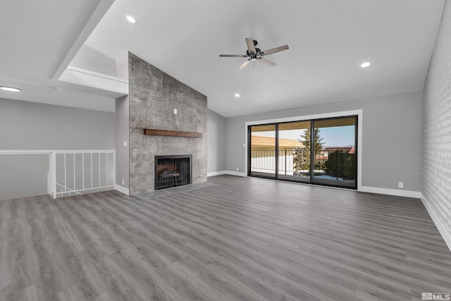 unfurnished living room with a tiled fireplace, ceiling fan, light hardwood / wood-style flooring, and lofted ceiling