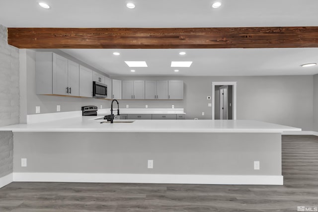 kitchen with hardwood / wood-style floors, kitchen peninsula, and appliances with stainless steel finishes