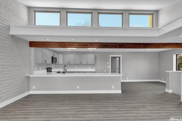 unfurnished living room featuring beamed ceiling, sink, and brick wall