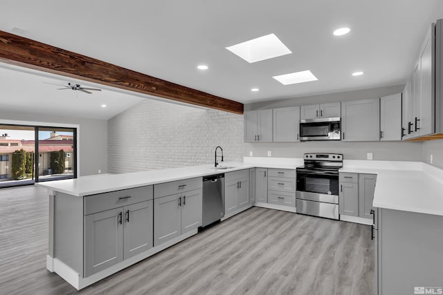 kitchen with gray cabinetry, kitchen peninsula, and appliances with stainless steel finishes