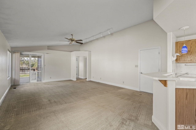 unfurnished living room with carpet flooring, track lighting, vaulted ceiling, and ceiling fan