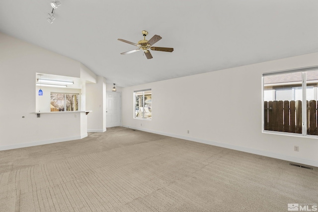 unfurnished living room featuring ceiling fan, a healthy amount of sunlight, light carpet, and vaulted ceiling