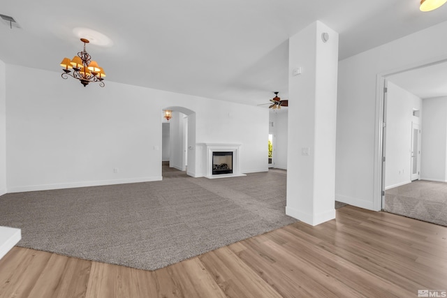 unfurnished living room with light hardwood / wood-style flooring and ceiling fan with notable chandelier