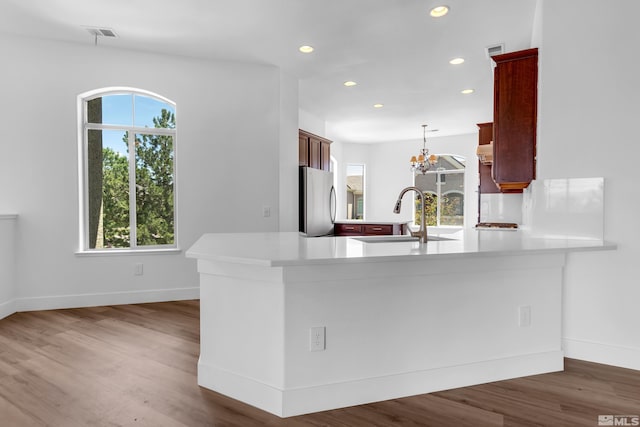 kitchen with stainless steel refrigerator, kitchen peninsula, pendant lighting, and dark hardwood / wood-style floors