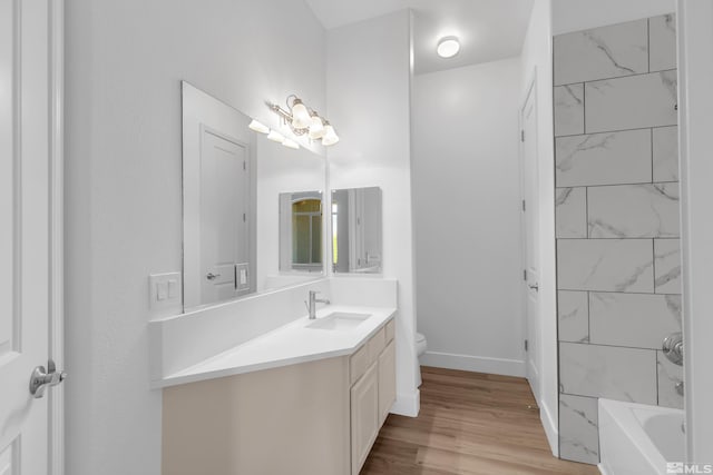 full bathroom with vanity, hardwood / wood-style flooring, toilet, and tiled shower / bath