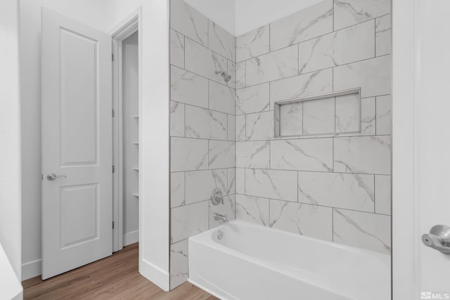 bathroom with hardwood / wood-style flooring and tiled shower / bath