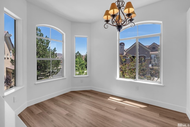 unfurnished dining area featuring a notable chandelier and light hardwood / wood-style floors