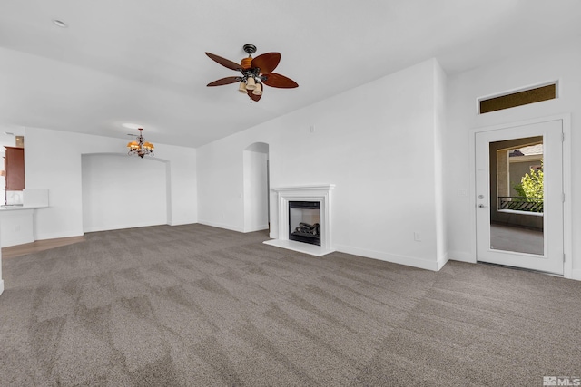 unfurnished living room featuring carpet flooring and ceiling fan with notable chandelier