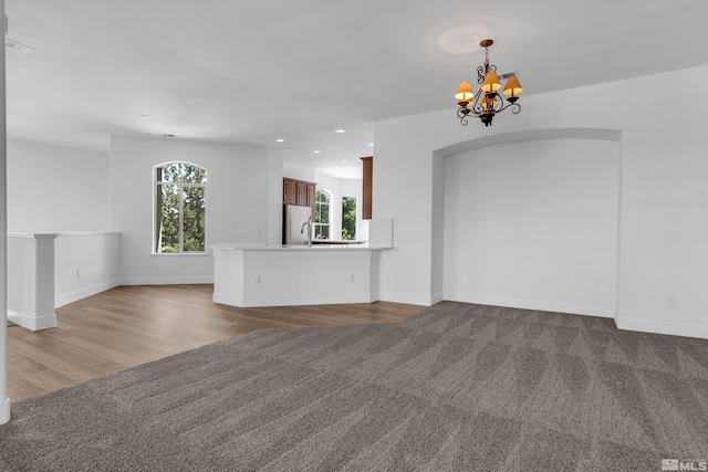 unfurnished living room featuring hardwood / wood-style flooring, a notable chandelier, and sink