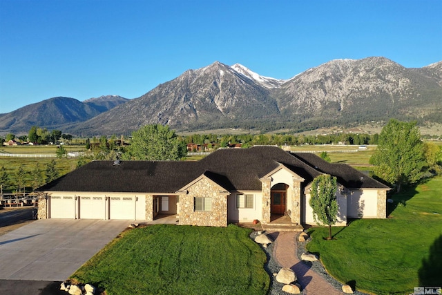 view of front of house featuring a mountain view, a front yard, and a garage