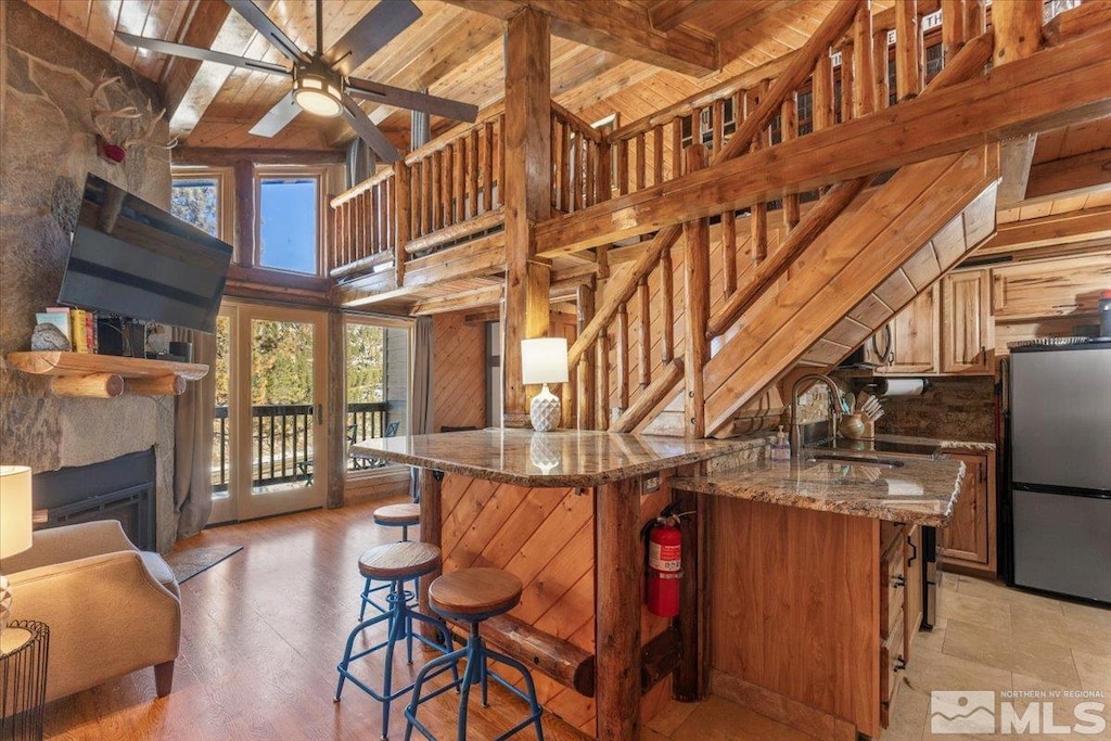 kitchen with stainless steel fridge, wooden ceiling, sink, and wooden walls