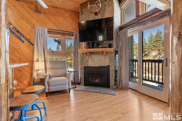 sitting room featuring hardwood / wood-style floors, wood walls, a fireplace, and high vaulted ceiling