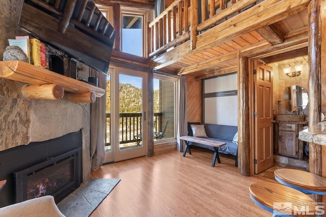 living area featuring beam ceiling, wood walls, and light hardwood / wood-style flooring