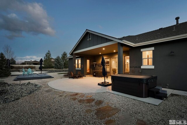 back house at dusk with a patio and a hot tub