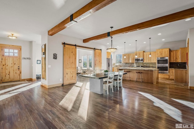 dining space featuring beamed ceiling, a barn door, and dark hardwood / wood-style floors