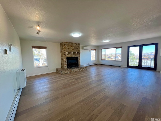 unfurnished living room featuring hardwood / wood-style floors, plenty of natural light, a fireplace, and a textured ceiling