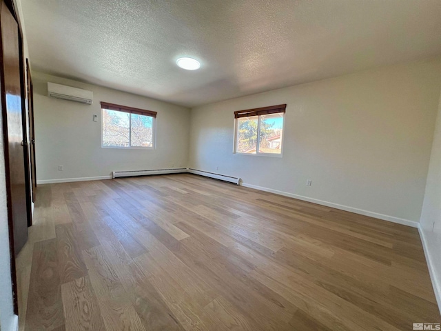 spare room with a textured ceiling, light wood-type flooring, and an AC wall unit