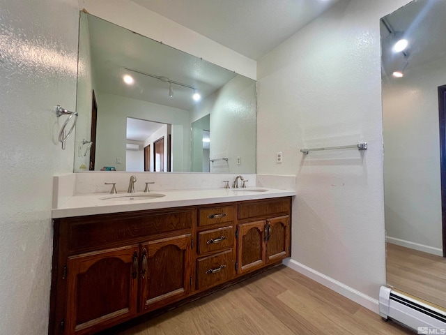 bathroom with hardwood / wood-style floors, vanity, and a baseboard radiator