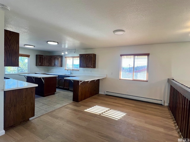 kitchen with kitchen peninsula, a kitchen bar, light wood-type flooring, and a baseboard radiator