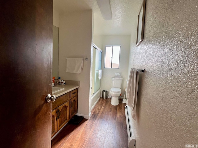 full bathroom with hardwood / wood-style floors, vanity, bath / shower combo with glass door, toilet, and a textured ceiling