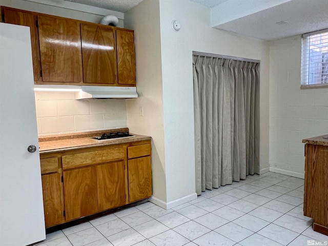 kitchen with gas stovetop, light tile patterned floors, a textured ceiling, and tasteful backsplash