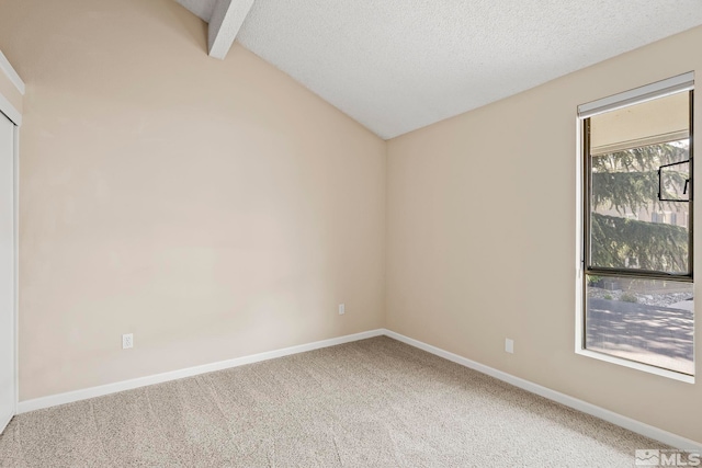 empty room featuring vaulted ceiling with beams, carpet floors, and a textured ceiling