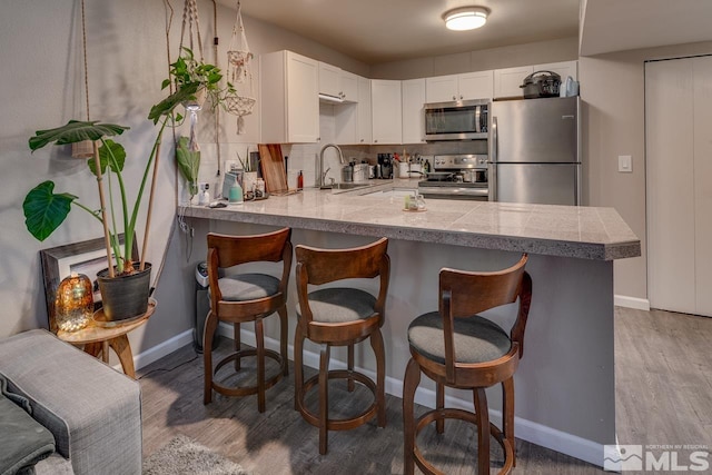 kitchen featuring kitchen peninsula, white cabinetry, decorative backsplash, and appliances with stainless steel finishes