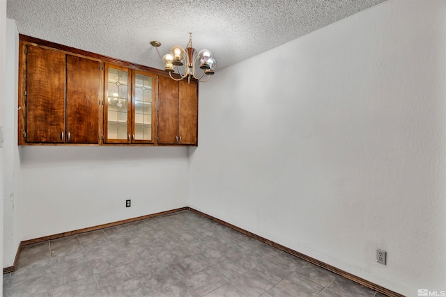 unfurnished room with a notable chandelier and a textured ceiling