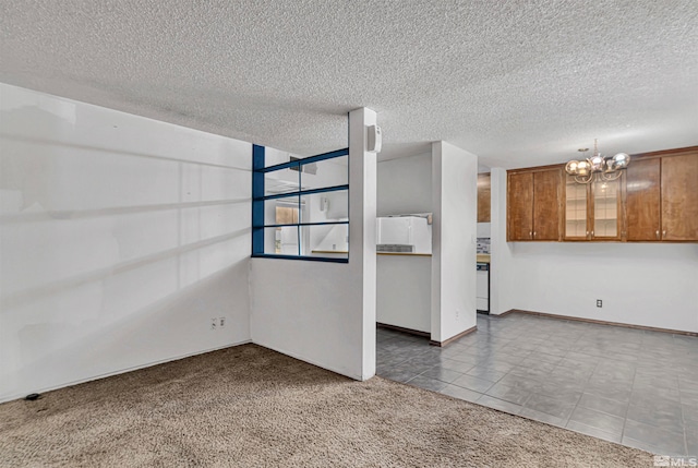 unfurnished room featuring carpet, a textured ceiling, and a notable chandelier