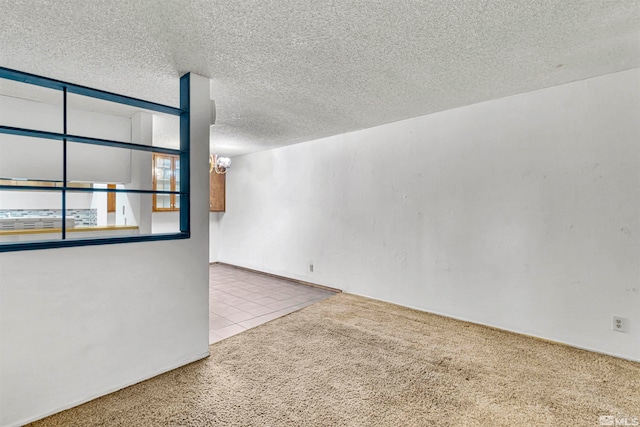 carpeted empty room with a chandelier and a textured ceiling