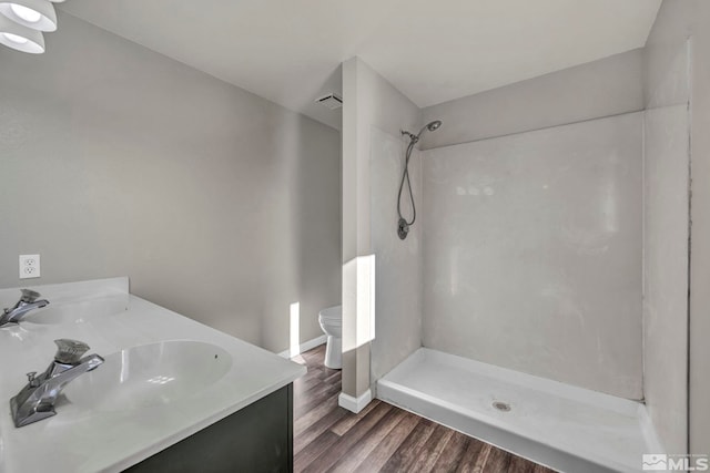 bathroom with hardwood / wood-style floors, vanity, toilet, and walk in shower