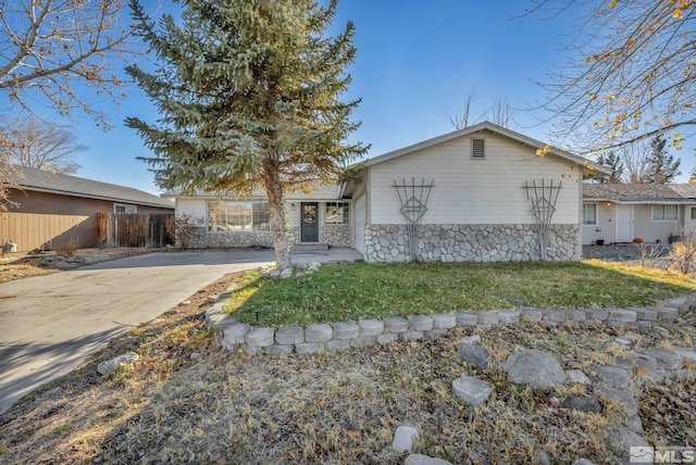 ranch-style house featuring stone siding, fence, and a front lawn