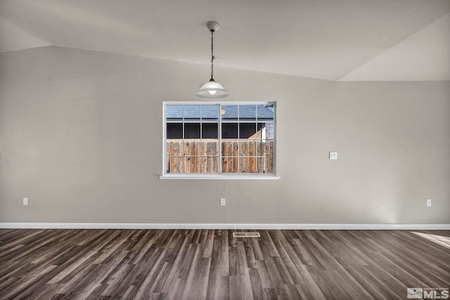 spare room featuring vaulted ceiling and dark wood-type flooring