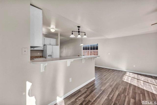 kitchen featuring a kitchen breakfast bar, hanging light fixtures, vaulted ceiling, dark hardwood / wood-style floors, and white fridge with ice dispenser